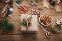 Wrapped Christmas present on wooden table with decoration objects — Stock Photo