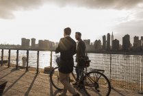 Two businessmen with bicycle walking along East River, New York City, USA — Stock Photo