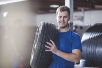 Young male mechanic with tire at workshop — Stock Photo