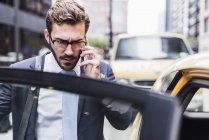 Businessman in Manhattan on cell phone entering a taxi, New York City, USA — Stock Photo
