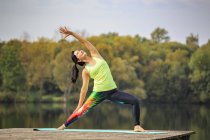 Young woman doing yoga exercise at a lake — Stock Photo