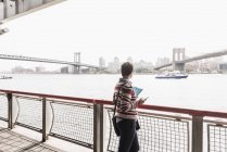 Donna in piedi a East River e guardando la vista, Stati Uniti, New York — Foto stock