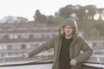Homme portant une veste à capuche debout sur la terrasse du toit — Photo de stock