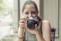 Ritratto di giovane donna sorridente che tiene una macchina fotografica — Foto stock