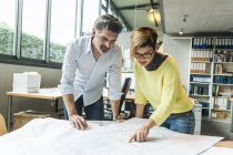 Arquitectos masculinos y femeninos discutiendo planta en oficina - foto de stock