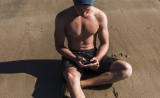 Молодой кавказский спортсмен с помощью смартфона на пляже, во Франции, на полуострове Крозон — стоковое фото