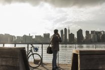 USA, New York City, businessman at East River on cell phone — Stock Photo