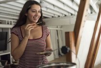 Smiling young woman painting with oil and brush — Stock Photo