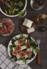 Plate of mixed lettuce with fresh figs, goat cheese and olive oil — Stock Photo