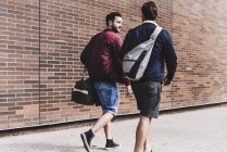 Deux amis avec des sacs de sport marchant sur la chaussée — Photo de stock