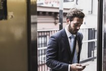 Молодой бизнесмен пользуется метро и смартфоном — стоковое фото