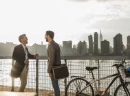 Deux hommes d'affaires debout à vélo à East River, New York, États-Unis — Photo de stock