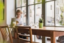 Mujer joven con teléfono celular y tableta en un café - foto de stock