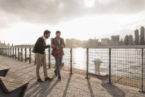 Zwei junge Männer zu Fuß entlang des East River und mit Handy, New York City, USA — Stockfoto