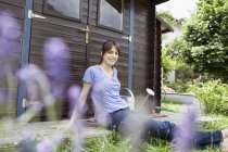 Smiling caucasian woman sitting at garden shed — Stock Photo