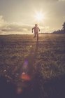 Silhouette de garçon courant sur une prairie au contre-jour — Photo de stock