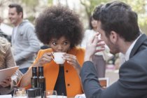 Two colleagues talking and drinking coffee at outdoor cafe — Stock Photo