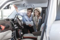 Rivenditore di auto che mostra la nuova auto alla donna — Foto stock