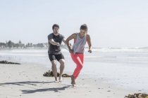 Young man and woman exercising on beach — Stock Photo