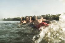 Glückliche Freunde schwimmen und planschen im Fluss — Stockfoto