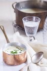 Closeup view of Vichyssoise soup in pot with glass of water — Stock Photo
