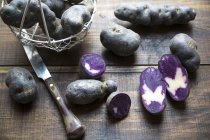 Halved and whole purple potatoes — Stock Photo