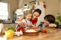 Glückliche Familie in der Küche, die Pizza zubereitet — Stockfoto
