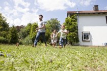 Famille caucasienne insouciante courir dans le jardin — Photo de stock