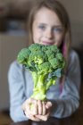 Ragazza in possesso di broccoli guardando la fotocamera — Foto stock