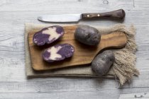 Pommes de terre violettes coupées en deux et entières — Photo de stock