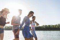 Amici felici che camminano al fiume in estate — Foto stock