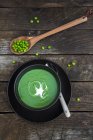 Bowl of pea soup, peas on wooden spoon — Stock Photo