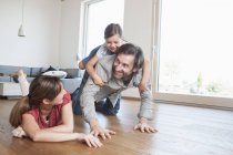Familia feliz tendida en el suelo, jugando con su hija - foto de stock