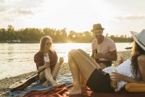 Freunde entspannen bei Sonnenuntergang am Flussufer — Stockfoto