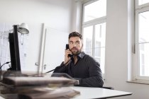 Uomo caucasico alla scrivania in ufficio che parla al telefono — Foto stock