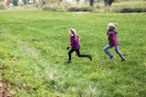 Ragazzo e ragazza in esecuzione su prato verde — Foto stock