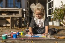 Bionda pittura bambina con i colori delle dita sulla terrazza — Foto stock