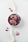 Чаша из сушеных цветов роз и кружева на белом фоне — стоковое фото