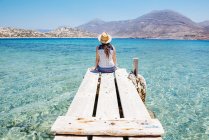 Grecia, Isole Cicladi, Amorgos, donna seduta sul bordo di un molo di legno, isola di Nikouria — Foto stock