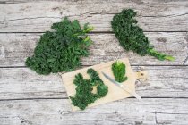 Fresh organic kale on wooden chopping board and grey wood — Stock Photo