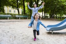 Padre in esecuzione con figlia nel parco giochi — Foto stock