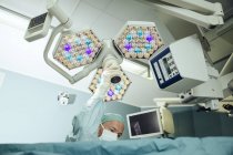 Enfermera de quirófano ajustando la luz de operación durante la cirugía - foto de stock