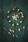 Box tree wreath with quail eggs and silver tea spoons on green wood — Stock Photo