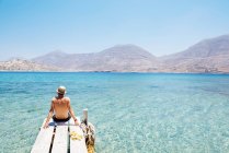 Grecia, Isole Cicladi, Amorgos, uomo seduto sul bordo di un molo di legno, isola di Nikouria — Foto stock