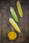 Organic corncobs on dark wood with maize in bowl — Stock Photo