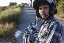Hombre en casco sentado en moto en carretera abierta - foto de stock