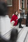 Jovem mulher sentada nas escadas além de seu cão — Fotografia de Stock