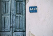 Cyclades, blue wooden door and taxi sign on the facade — Stock Photo