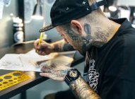 Tattoo artist designing motifs — Stock Photo