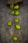 Wicker basket and organic pears on dark wood — Stock Photo